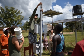 Students are installing a tall weather station with locals.