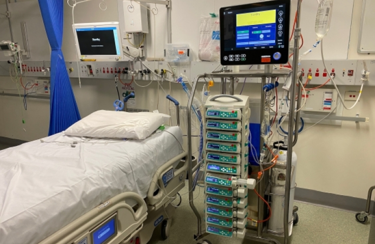 ICU equipment towers next to empty hospital bed