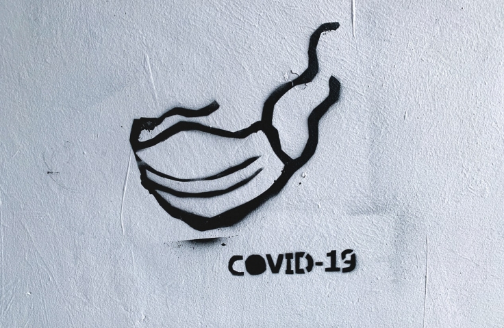 A black spray painted surgical mask with "COVID-19" underneath. 