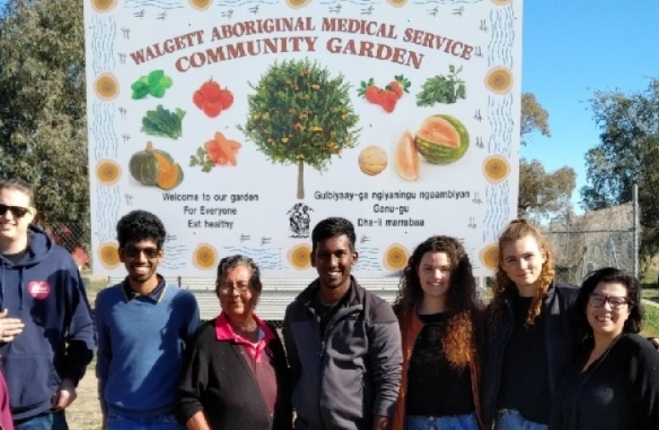 A group of people stand in front of a sign reading Walgett Aboriginal Medical Service Community Garden