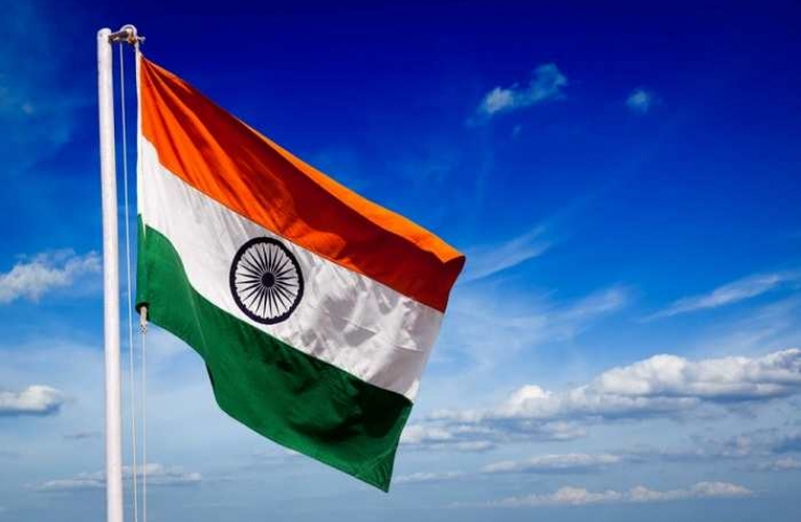 Indian flag on flag pole against background of sky and clouds