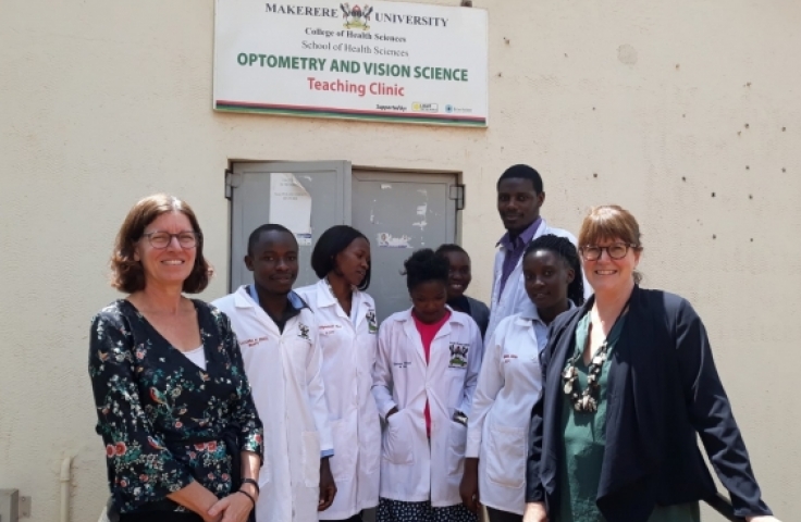 5 student optometrists stand with 2 UNSW staff outside Makerere University Optometry Clinic.