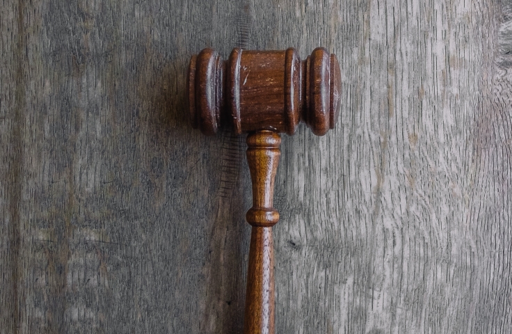 A brown gavel sits on its' side on a grey wooden surface.