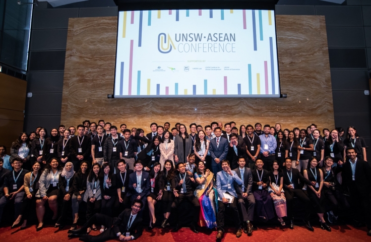 Participants of the UNSW ASEAN Conference in 2019 are standing on stage in a group smiling towards the camera.