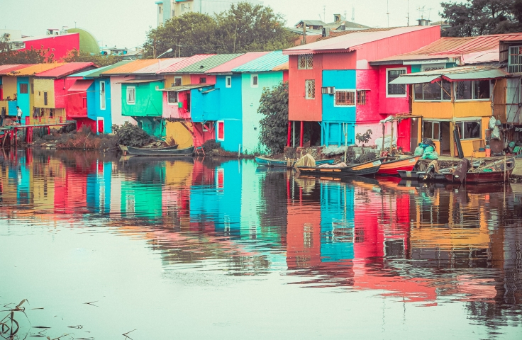 Colourful houses are situated next to a river.