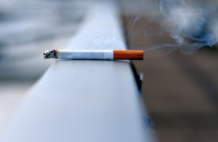 A lit cigarette resting on a balcony