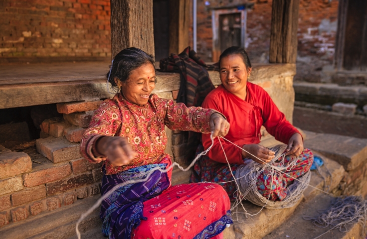 Nepali women spinning a wool in front of the house. Bhaktapur in Kathmandu valley.