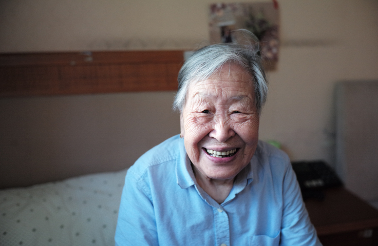An elderly South-East/East Asian person is smiling for the camera
