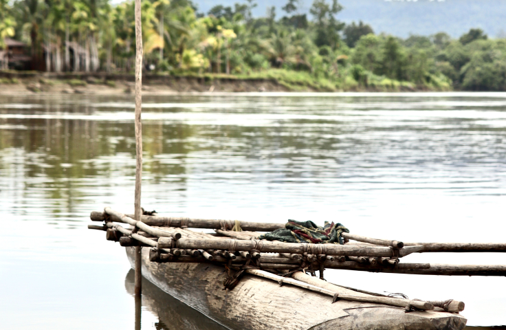An empty canoe sits on a tropical river