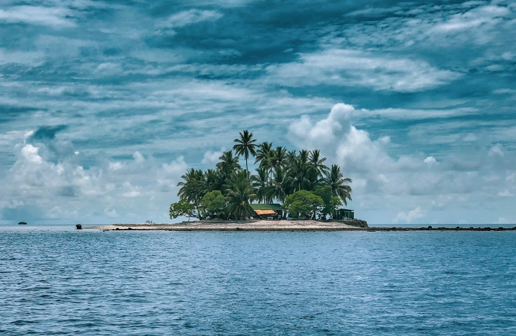 An island with green trees can be seen on the horizon.