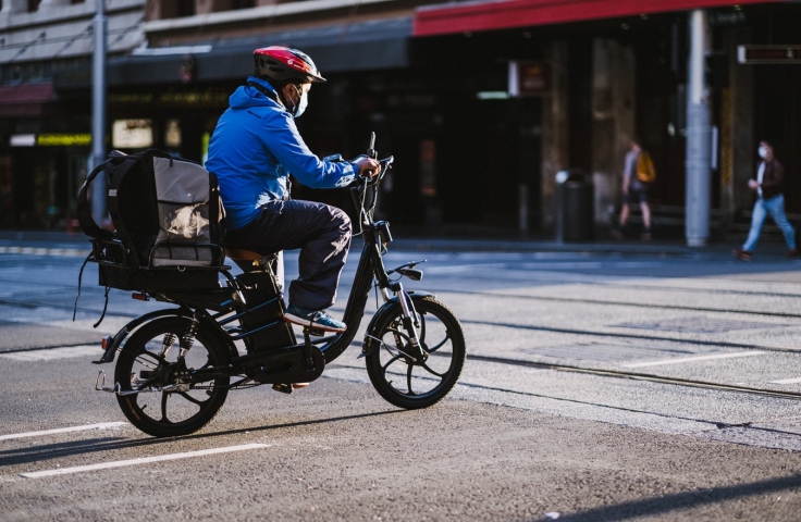 A man riding a bicycle wearing a blue jacket in Sydney.
