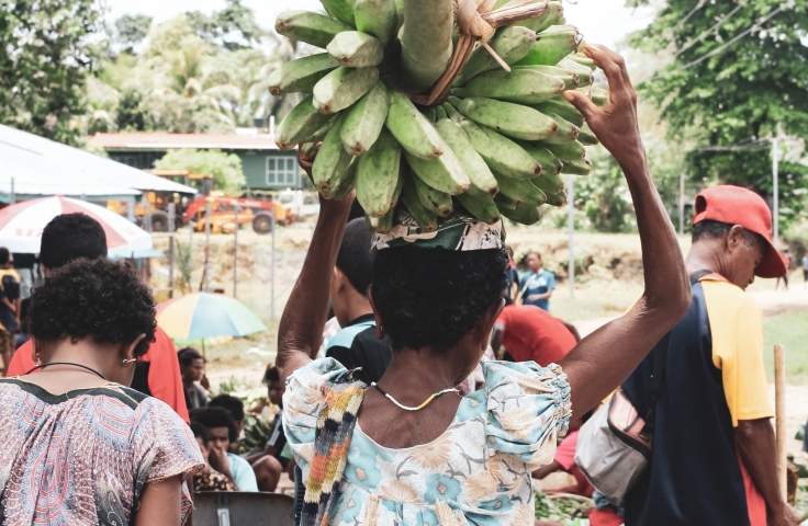 Women in Papua New Guinea are carrying bananas and shopping bags. 