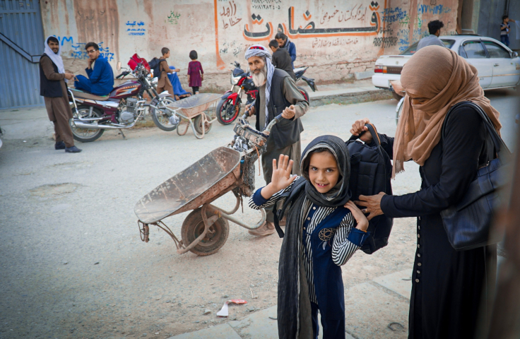 An Afghan girl is waving at the camera
